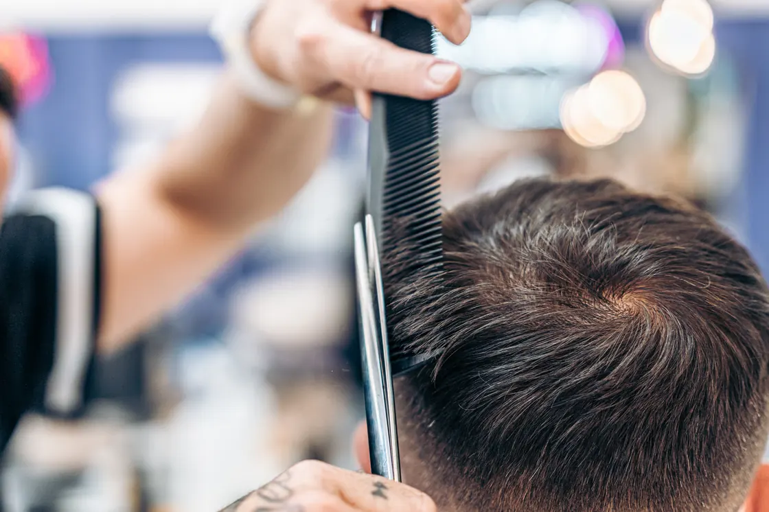 Close-up of a barber combing and cutting short hair