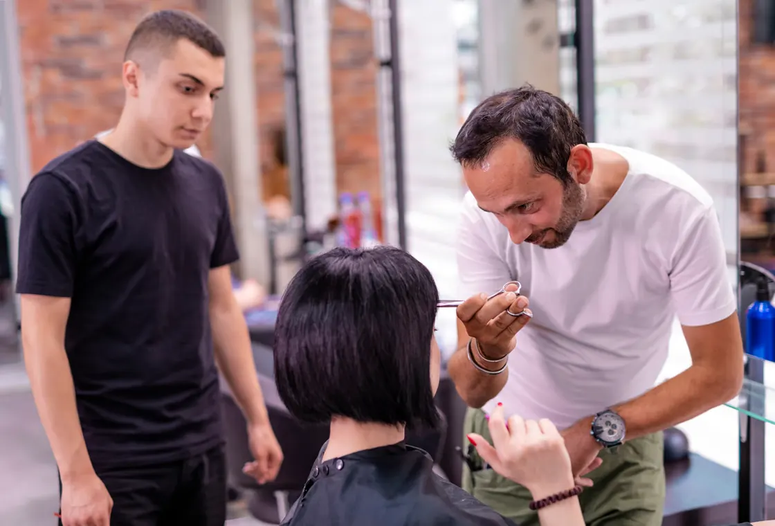 Instructor demonstrating a haircut to a barber student