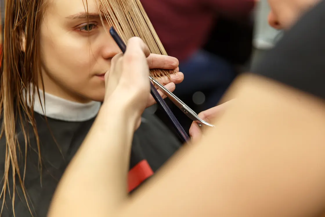 Stylist trimming a client's long hair with scissors