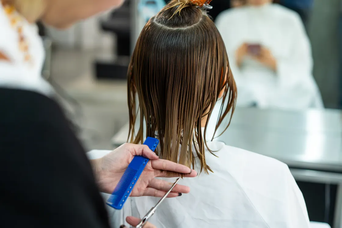 Student sectioning wet hair with a comb during a haircut