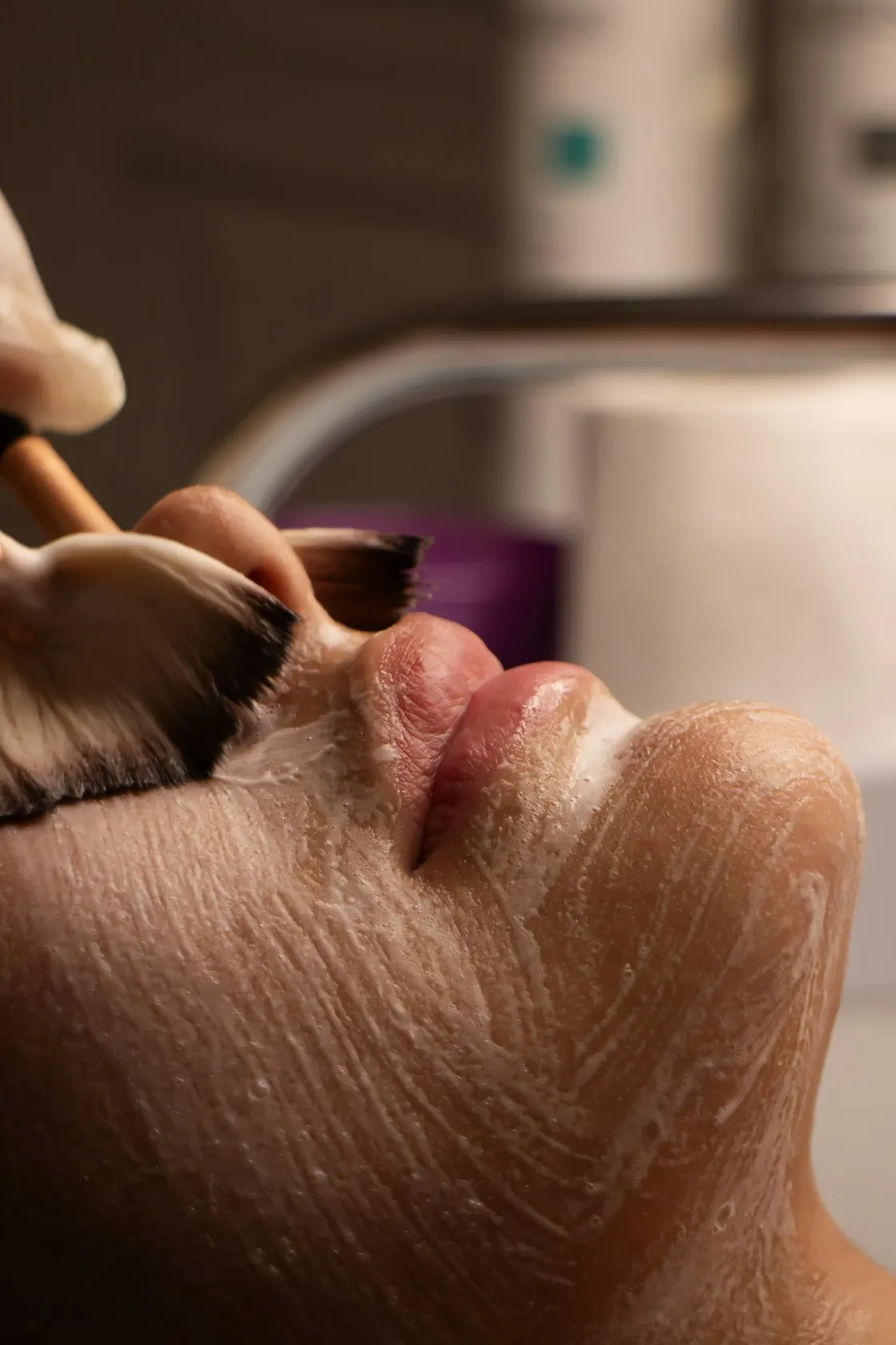 Esthetician applying a facial mask with a brush