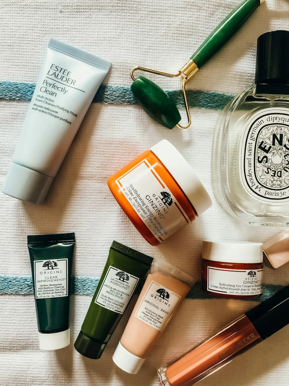 Skincare products and a jade roller laid out on a towel