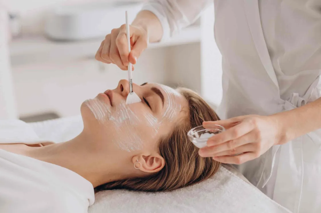 Esthetician applying a facial treatment with a brush