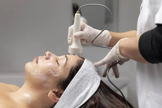 Esthetician using a skincare device on a client's face