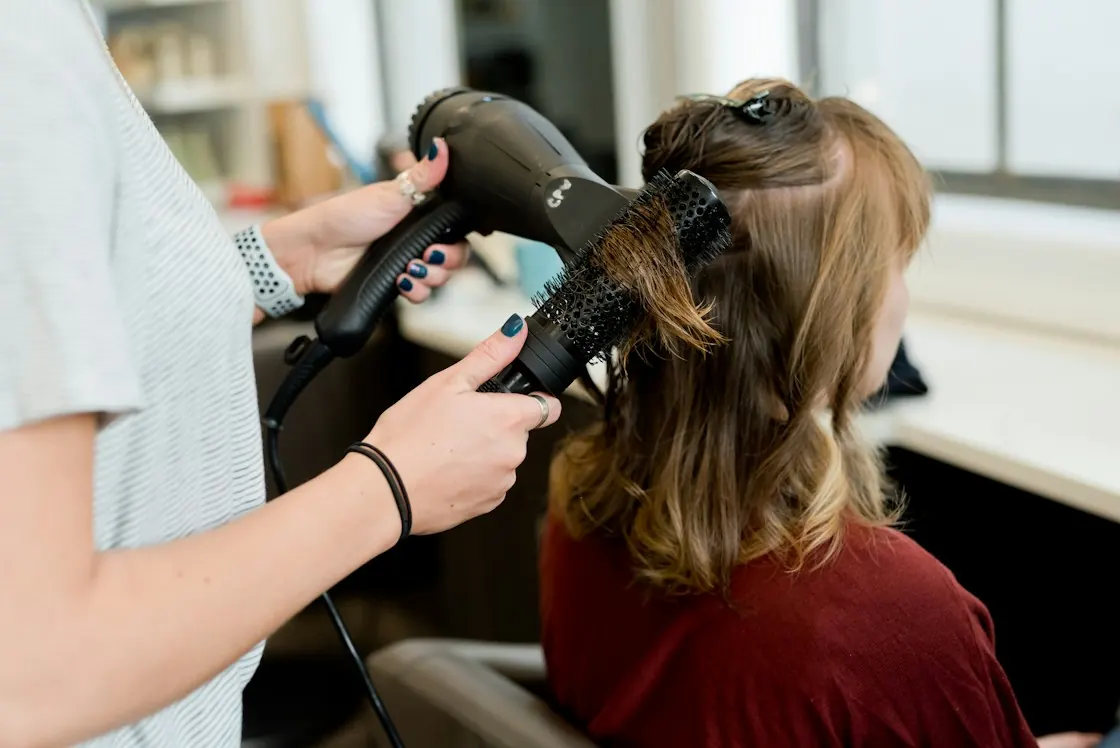 Professional hairstylist blow-drying a client's hair in a salon